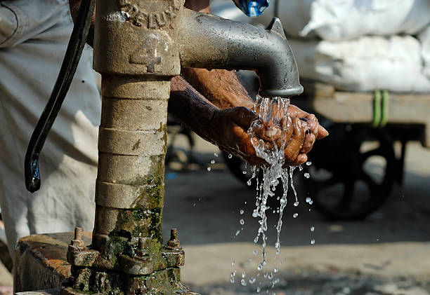 man washing hands at old fashioned community tap